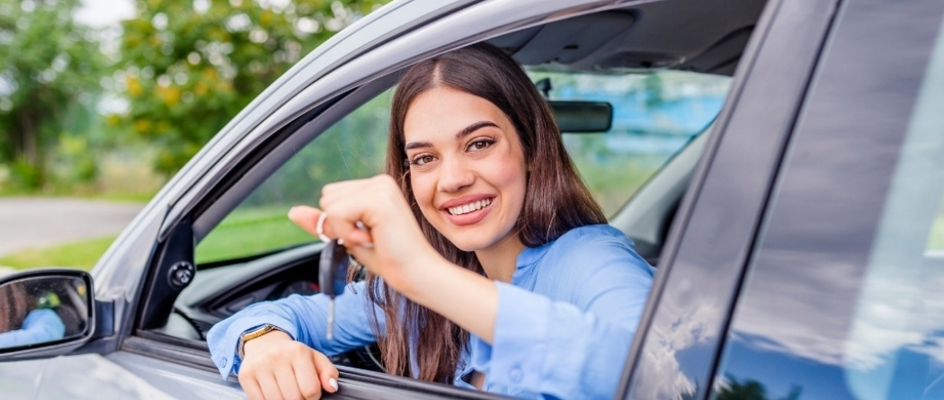 young girl holding car keys out of driver side window
