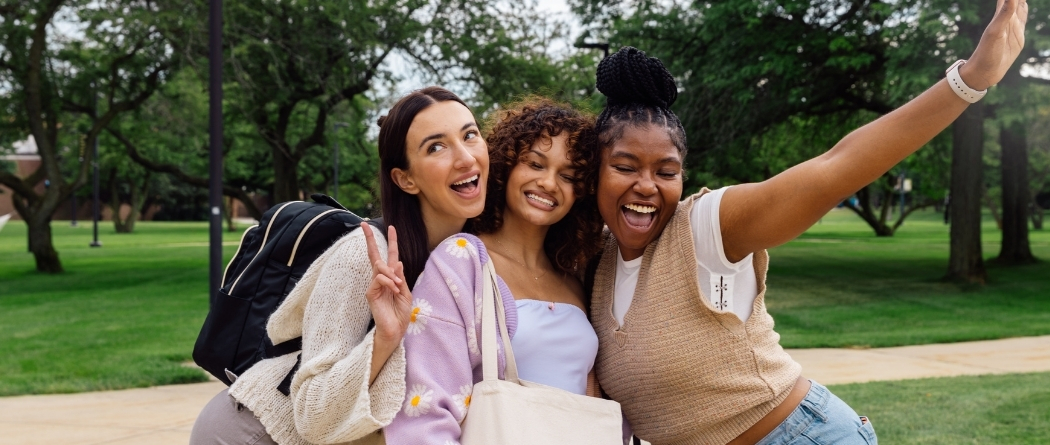 Three college aged girls pose for a picture.