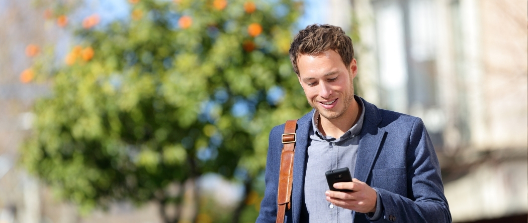 business man walking while looking at phone