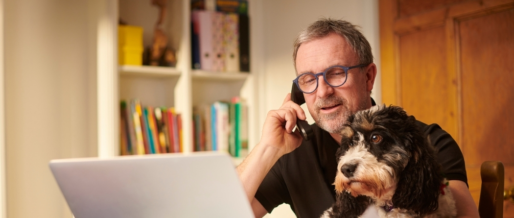 older man on laptop with dog in lap