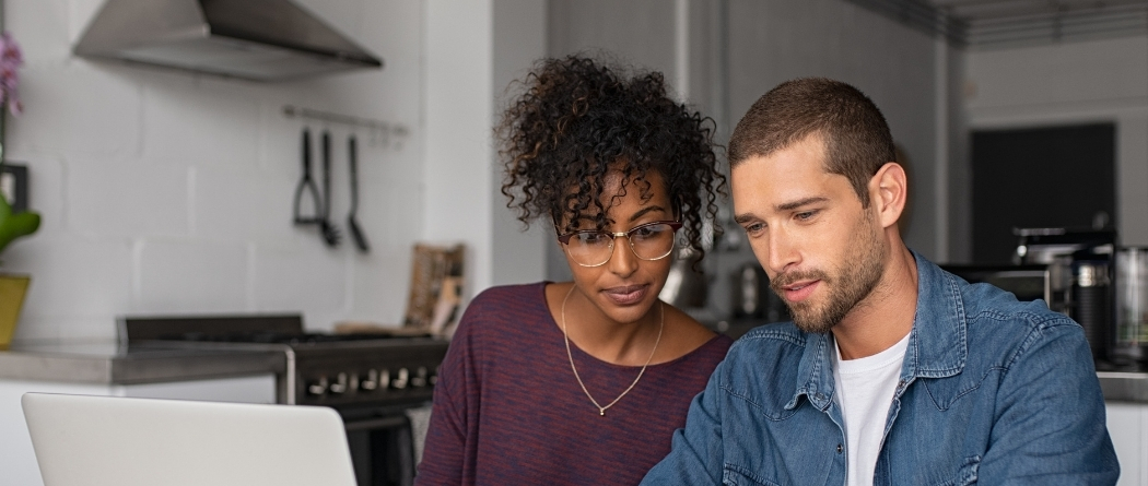 A young couple look at their laptop.
