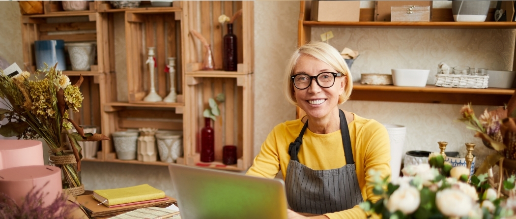 boutique business owner smiling at camera and on her laptop