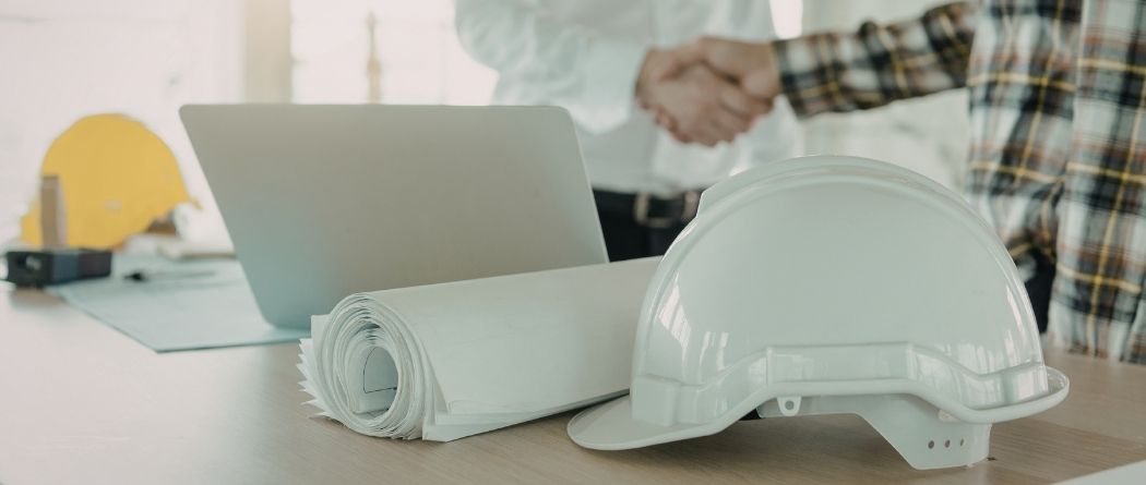 hard hat on a table with hands shaking in the background