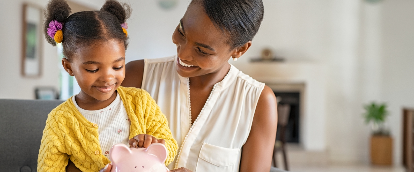 mother and young daughter putting money into a piggy bank