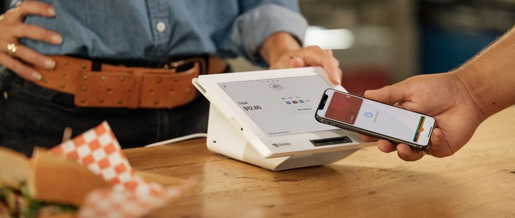 Customer taping phone on payment device called Clover