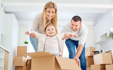 Couple pushing toddler in a box as they move into new home