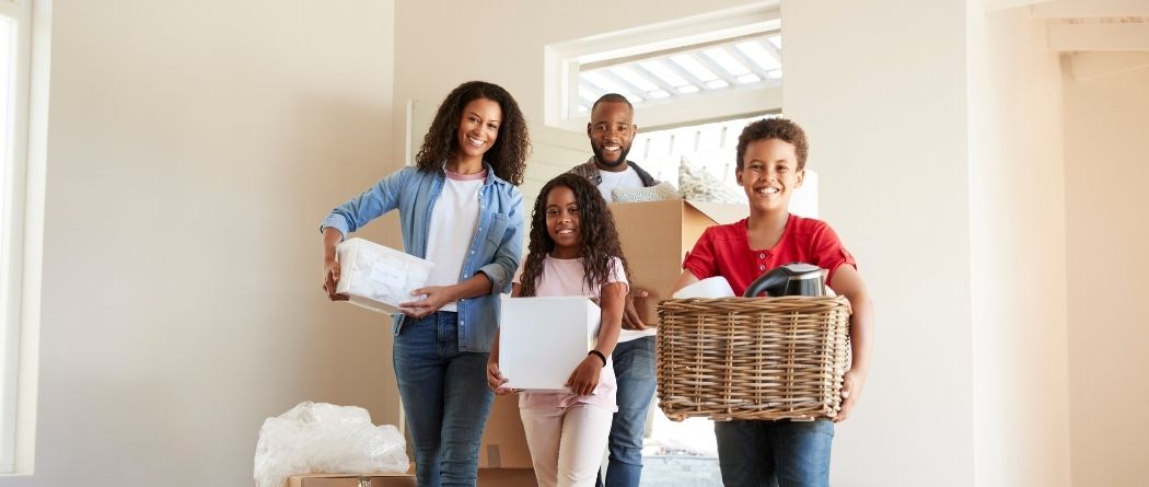 family carrying boxes into new home