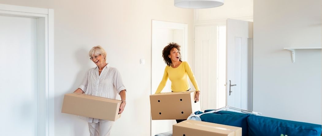 mother and daughter moving boxes into home