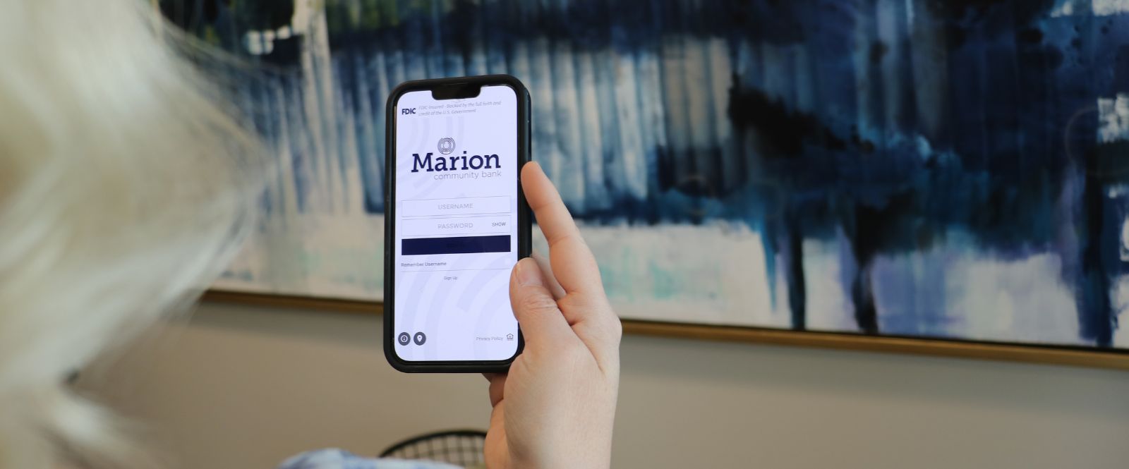Lady holding phone with Marion Banking Mobile App open