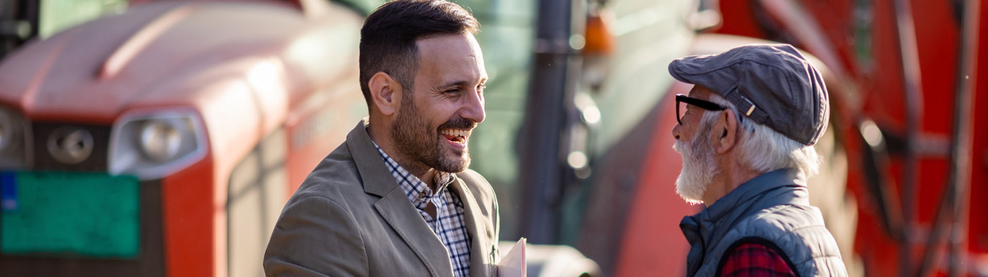 Two men smiling on talking on the sidewalk.