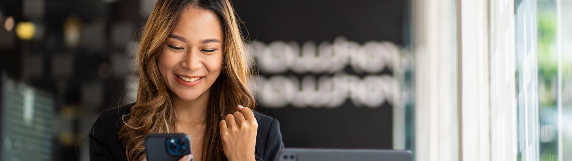 Woman smiling and looking at her phone.