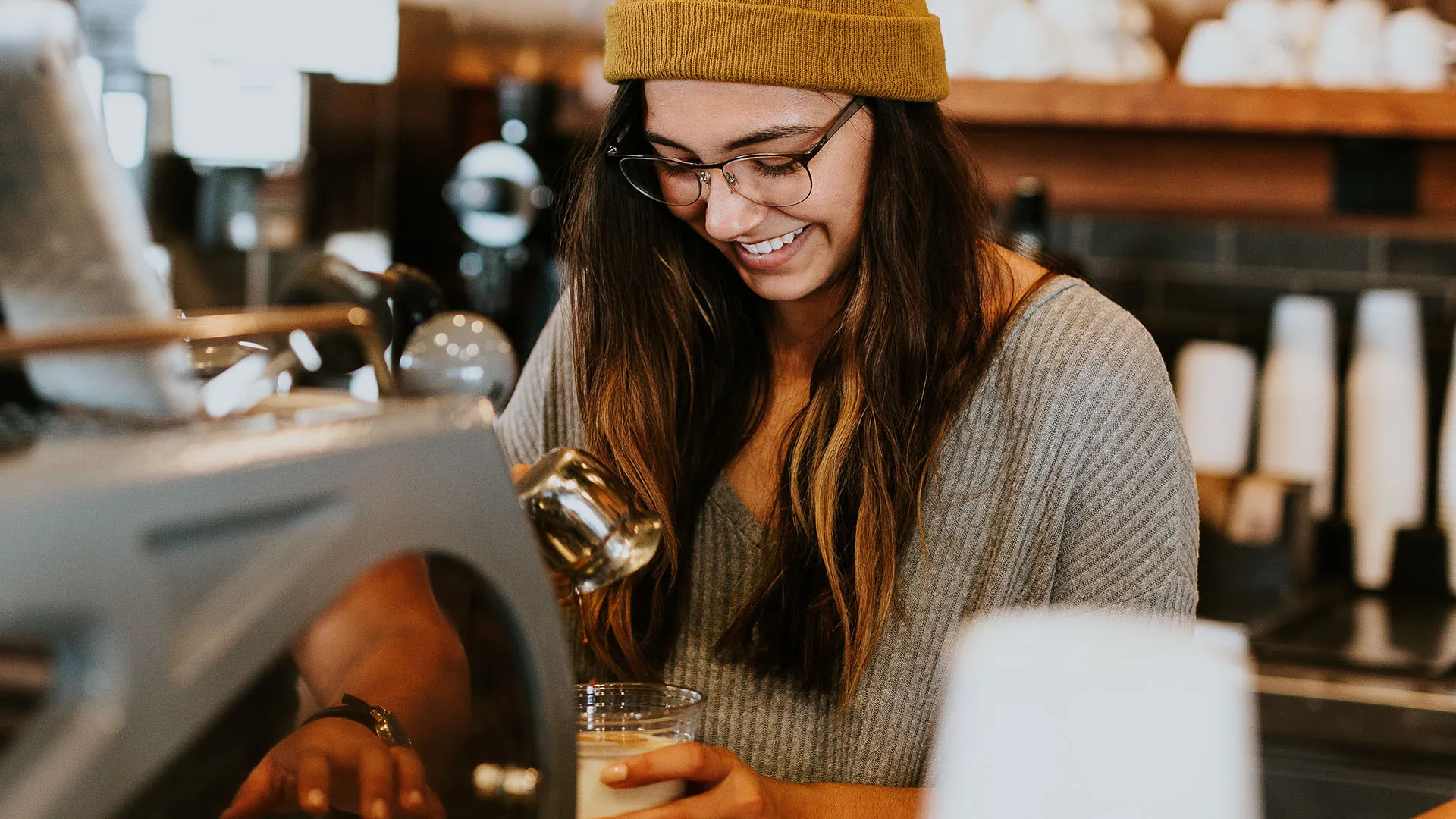 A woman working behind the counter at a coffee shop.