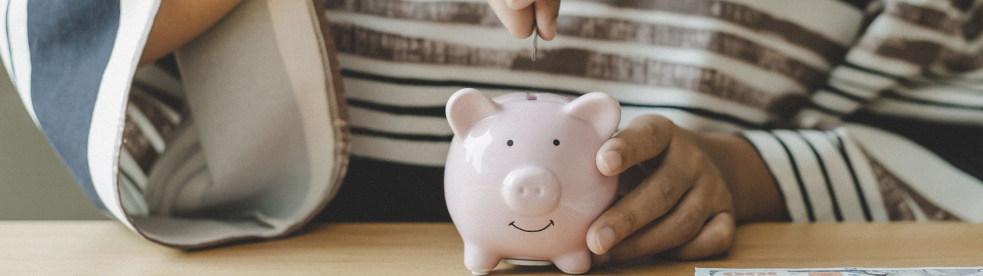 Woman placing a coin into a piggy bank.
